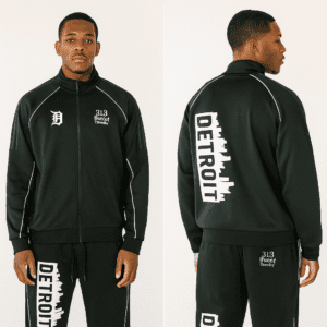 Front and back view of a 313 Emblems black zip-up tracksuit. The jacket features a cropped fit with Detroit skyline and sports team patches on the back. The matching flare joggers feature "DETROIT" in colorful block letters down the legs.