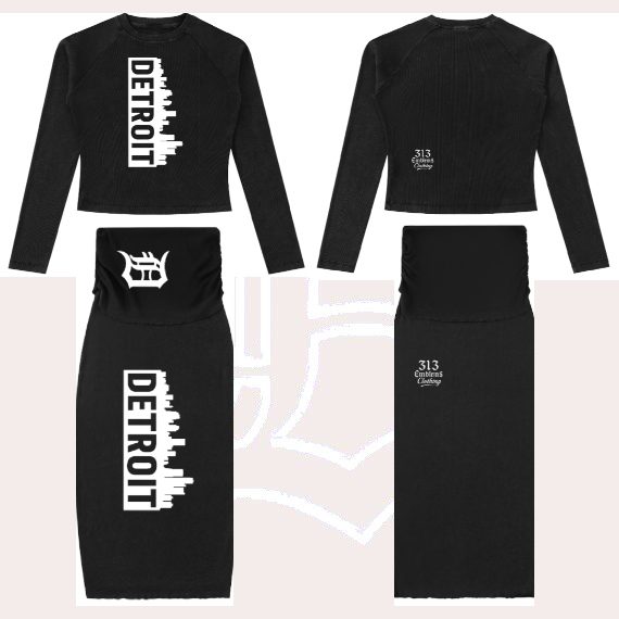 Flat lay view of a 313 Emblems black ribbed two-piece set featuring a long-sleeve crop top and midi skirt. Both pieces display the white vertical "DETROIT" skyline graphic and Gothic "D" branding. The set has a clean, urban, rockstar aesth